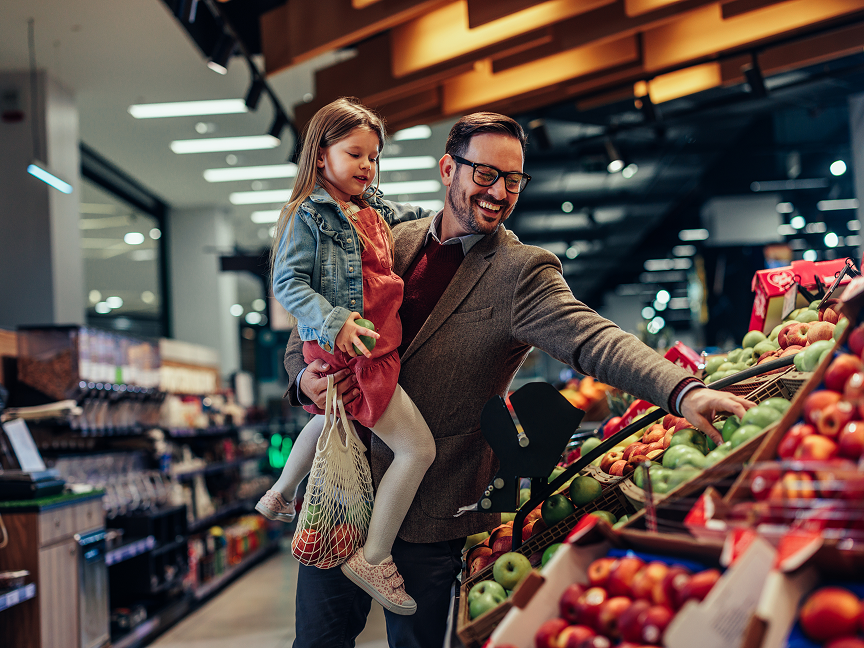A dad carrying his daughter while shopping at the grocery store
